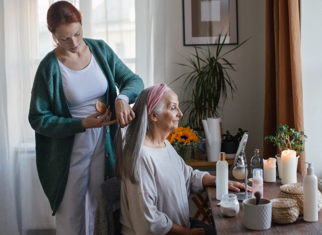 Caregiver helping her senior client with hairstyle. Caregiver helping her senior client with hairstyle.