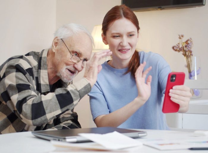 An elderly man and a young woman are talking on a video call over the Internet. They say goodbye to the interlocutor, smile and end the call. High quality FullHD footage